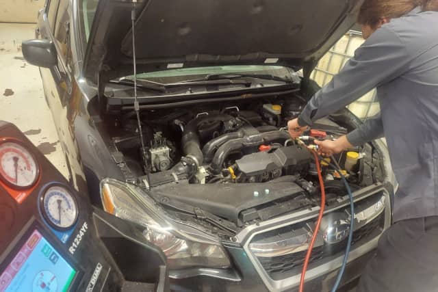 Technician performing A/C system pressure test. Hoover Street Auto Repair services auto air conditioning HVAC.